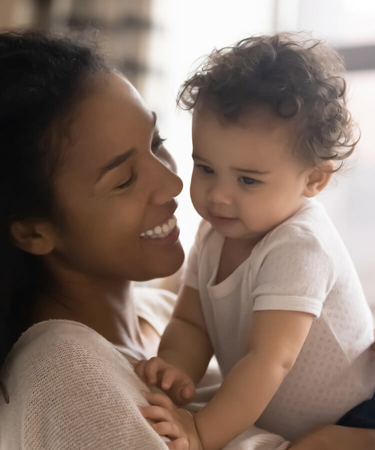 A mom smiling at her baby while carrying her