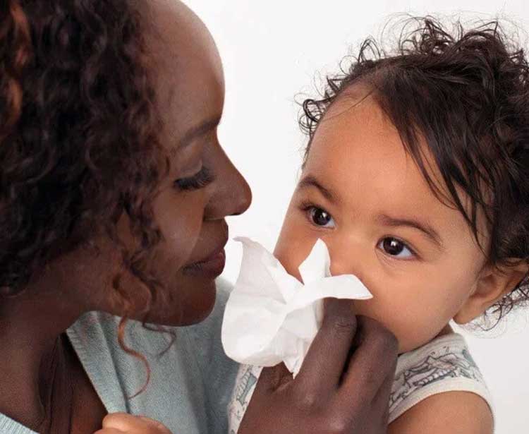 Mom holding a tissue to baby's nose