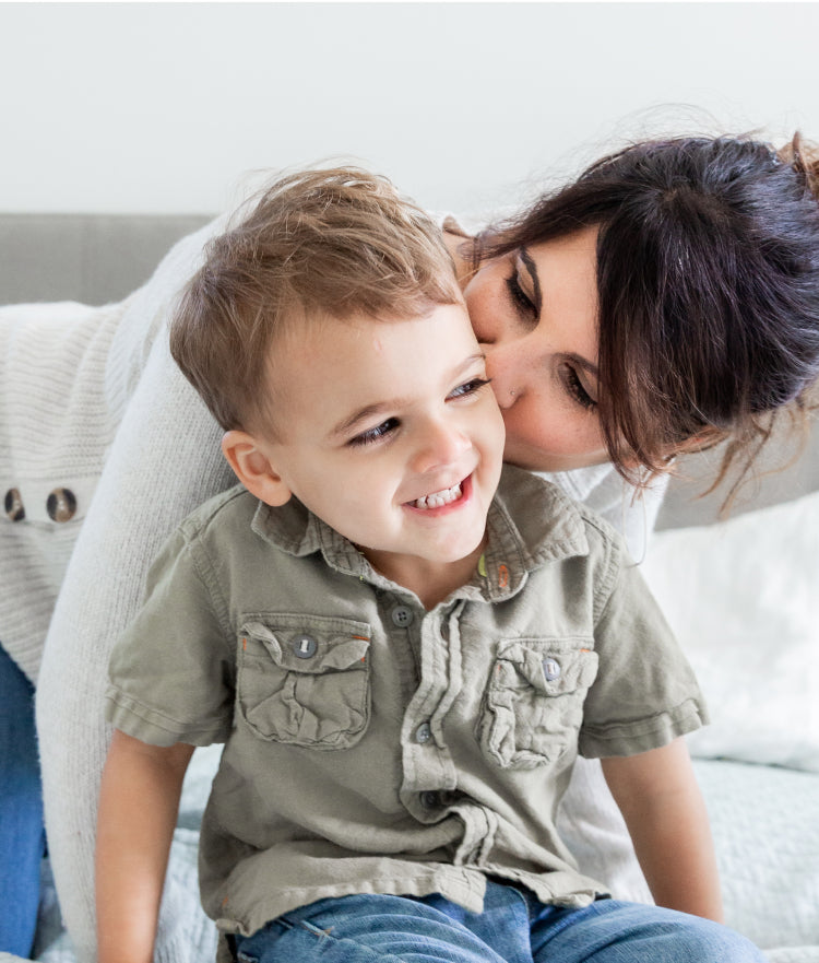 A mom kissing her kid wearing a polo shirt
