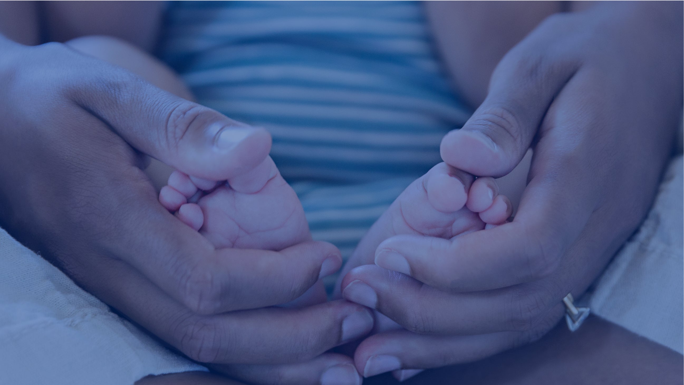 Infant's feet being held by a parent's hands