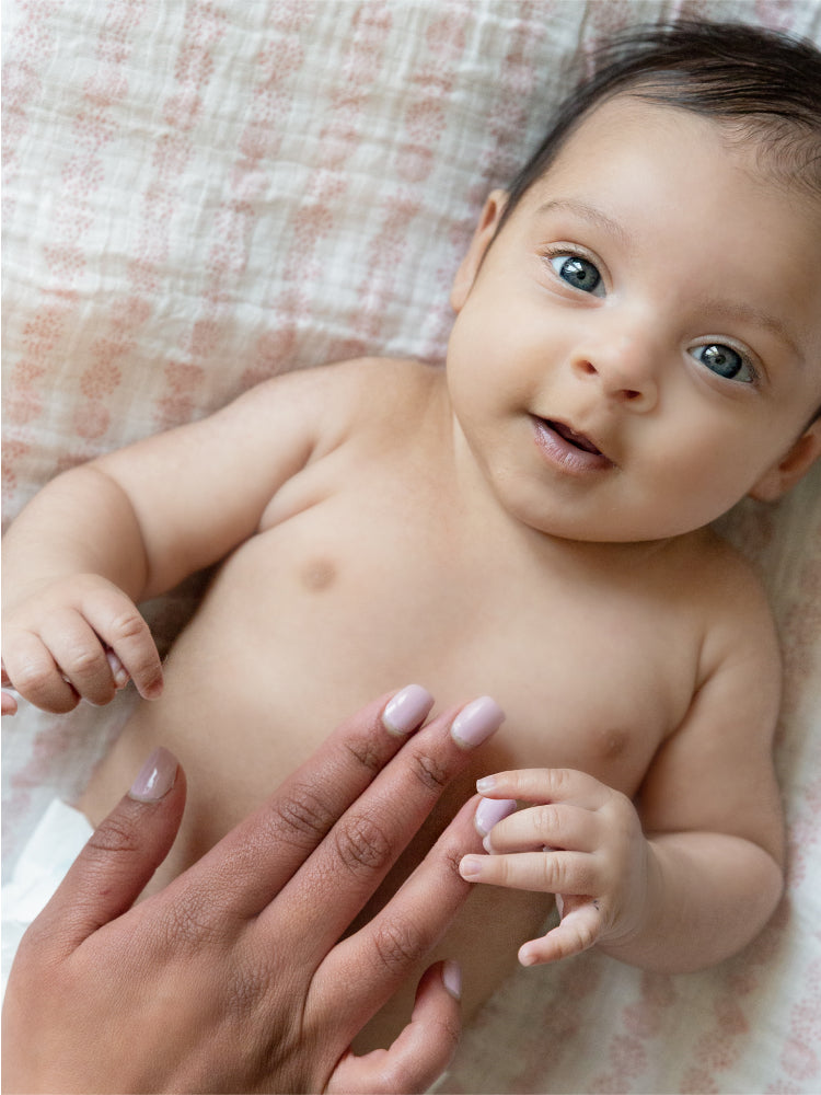 An infant with blue eyes, lying on its back looking at the camera