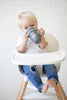 Sip Sip Hooray Happy Sippy Cup by Bella Tunno being held by a kid while in a high chair