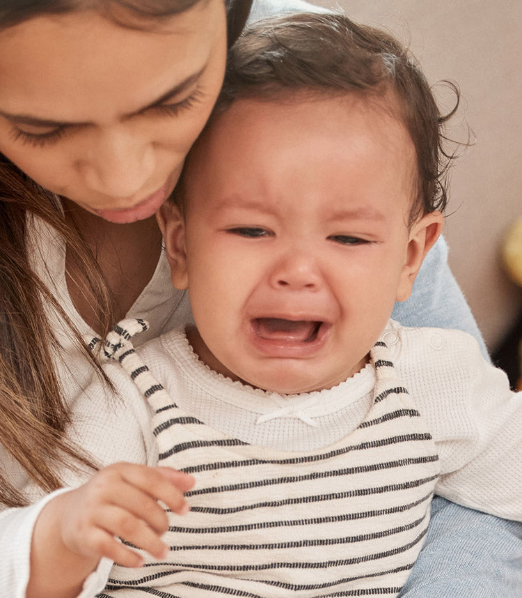 woman comforting crying baby in her lap