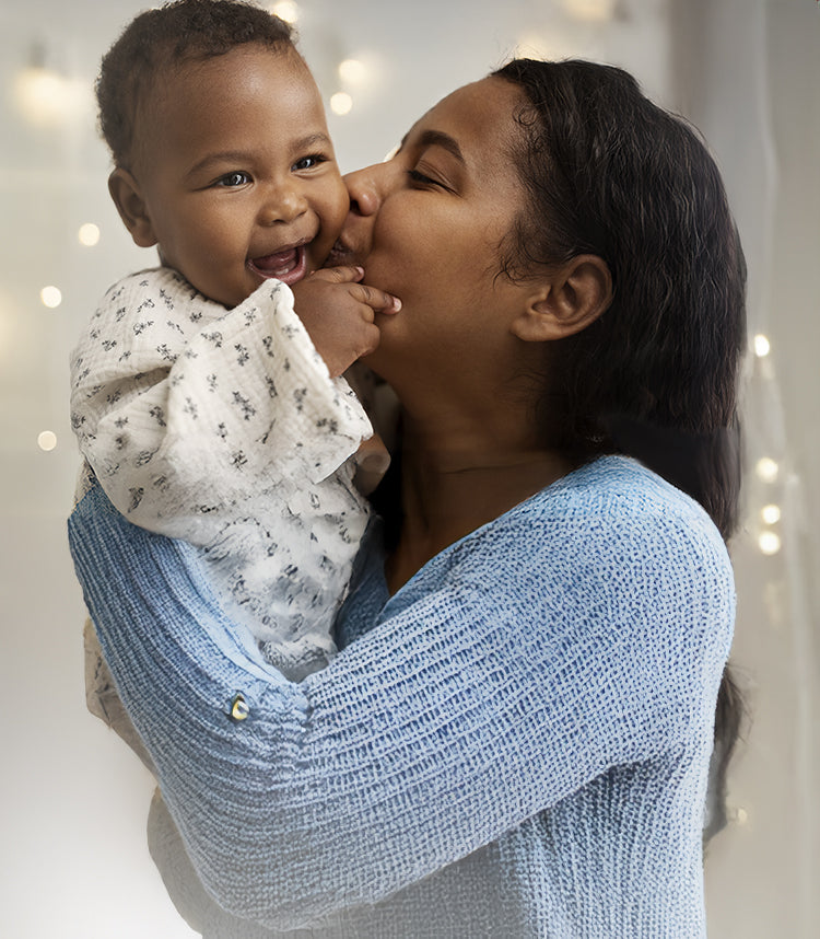 Mom holding and kissing smiling baby