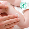 A mother's hand putting a lotion on a baby's leg with eczema