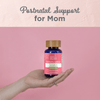 Moms Postnatal Lactation Support being held by a hand in pink background